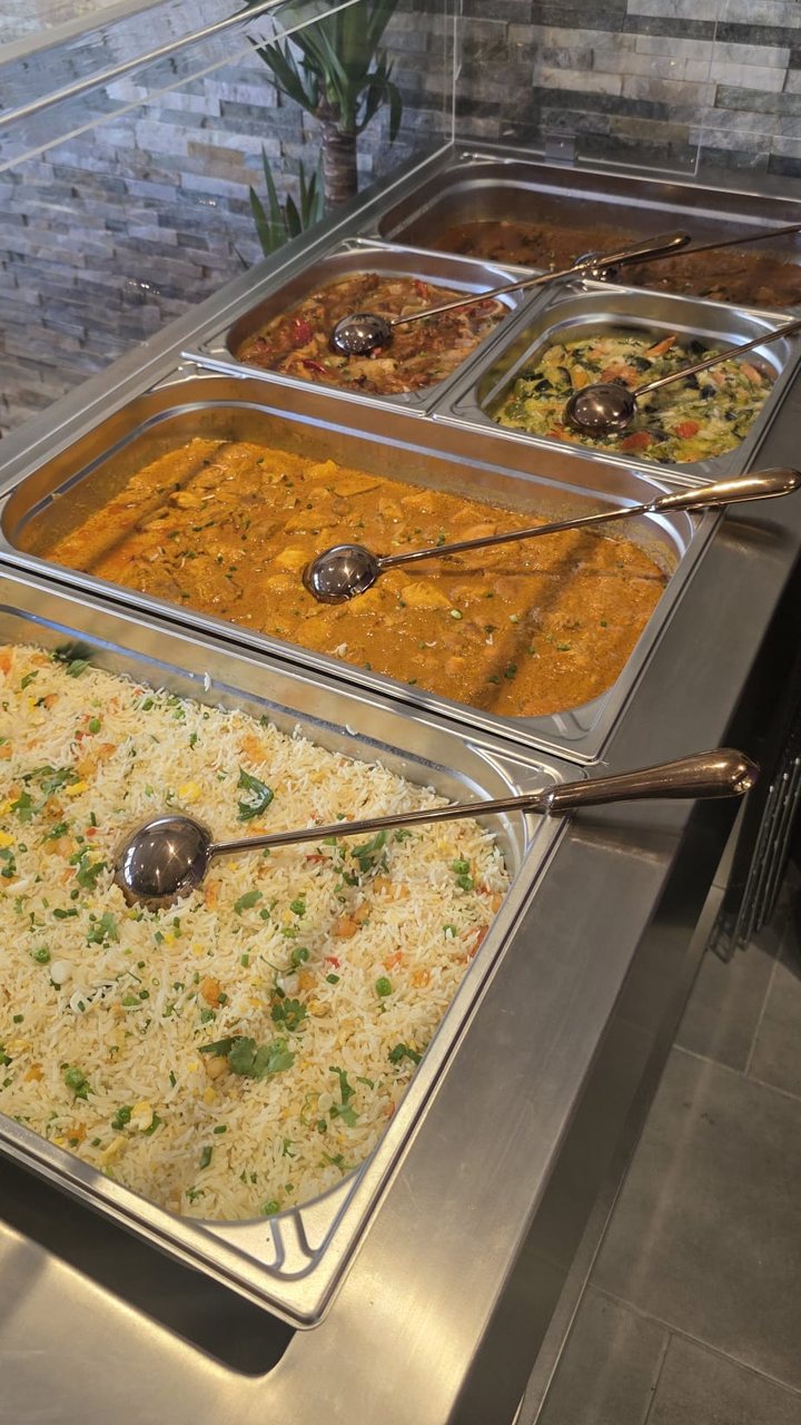 Bacs de curry, de légumes et de riz sauté tenus au chaud derrière une vitre
