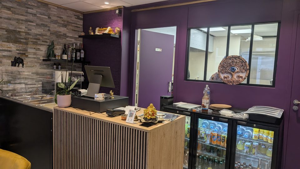 Le comptoir du restaurant, devant les murs violets et la cuisine vitrée