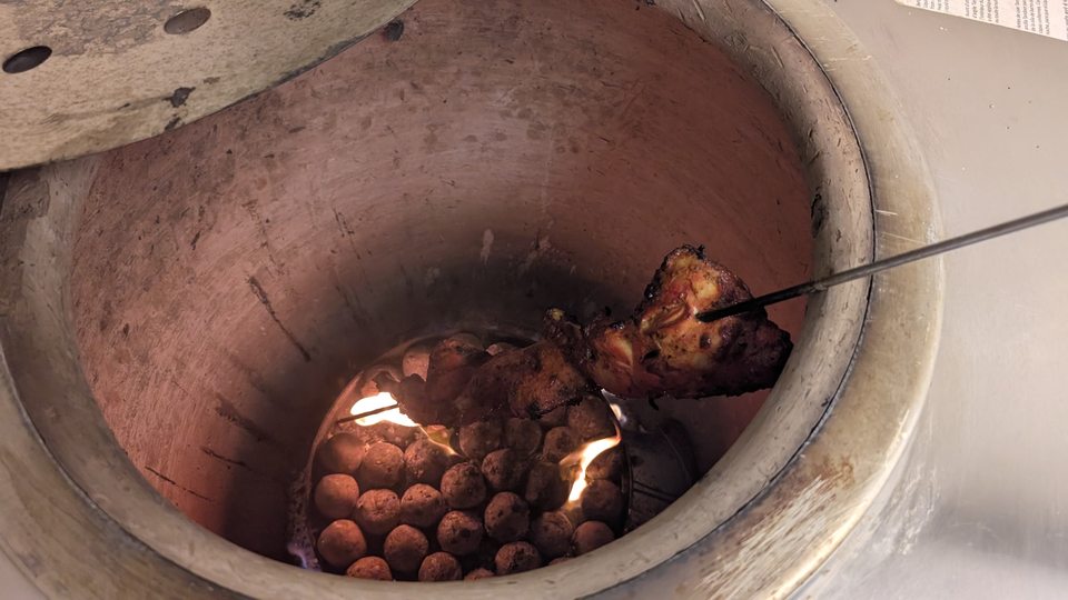Une brochette au-dessus des braises dans le four tandoor